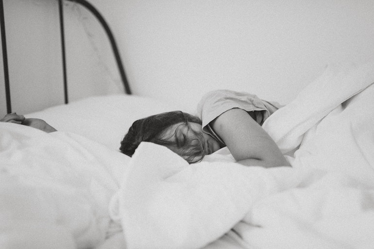 Une jeune femme dans un lit © Kinga Cichewicz / Unsplash