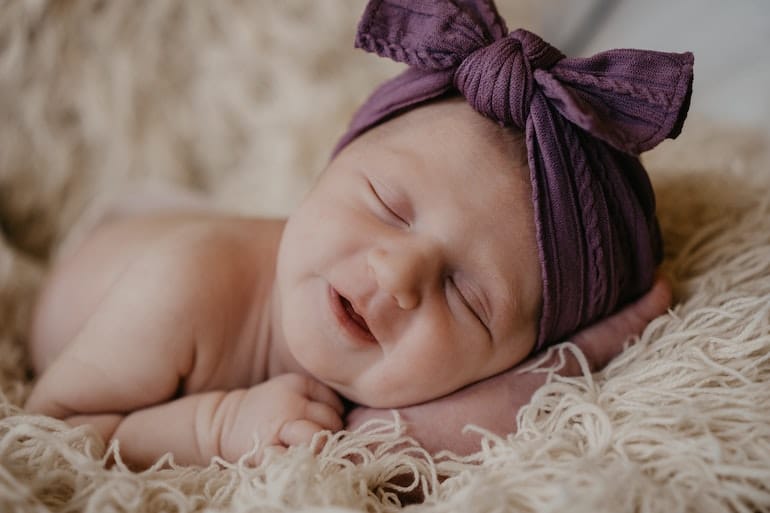 Un bébé fille endormi avec un bandeau violet sur la tête © Emmalee Couturier / Unsplash