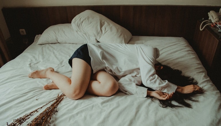 Une fille triste allongée sur son lit © Yuris Alhumaydy / Unsplash